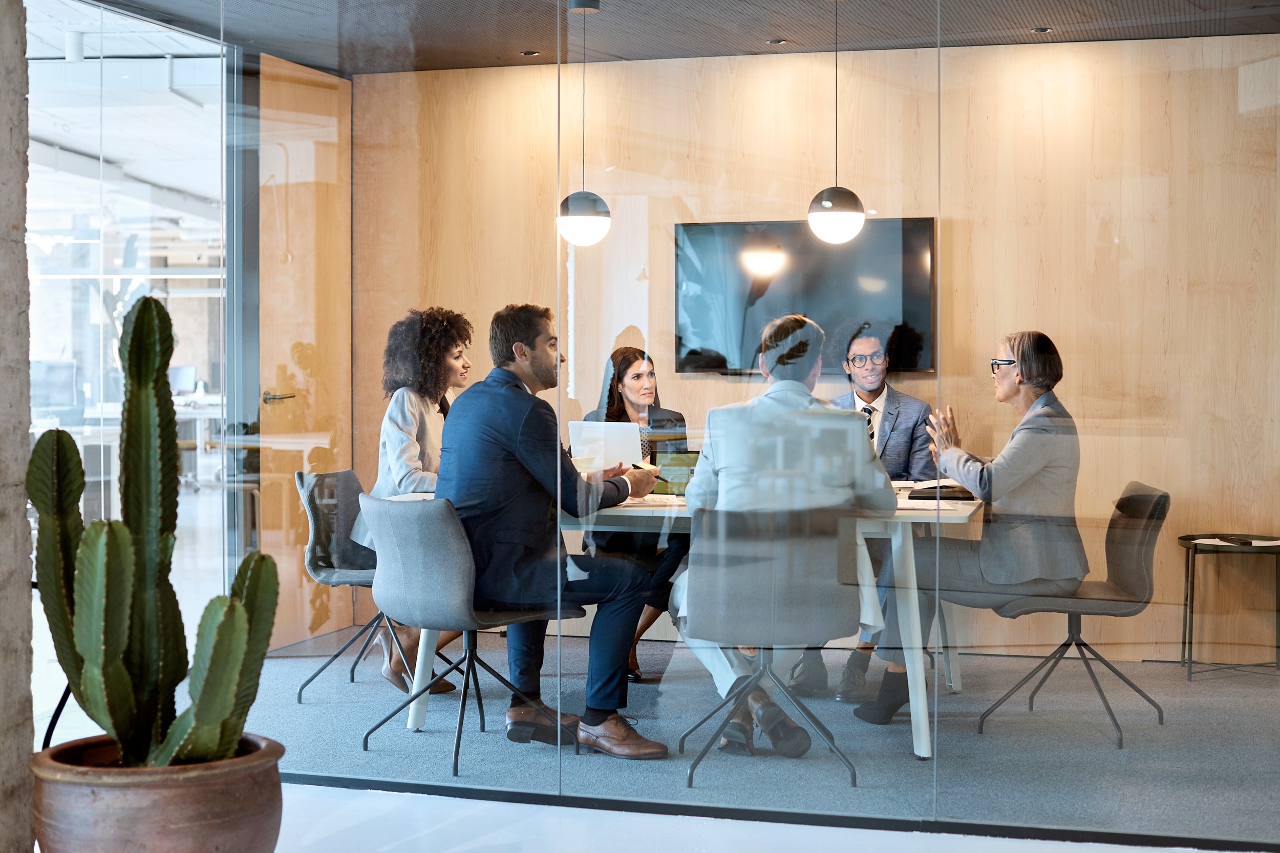 Business professional colleagues take a meeting inside a chic conference room.