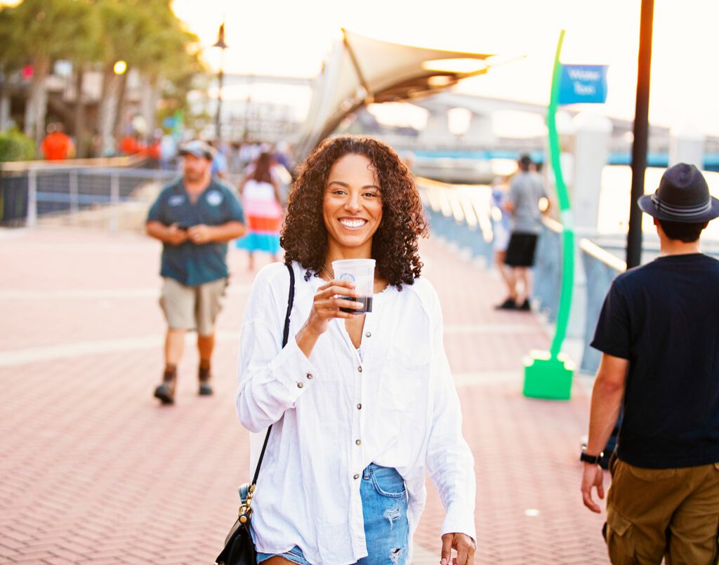 A woman smiles with a glass of wine at a Jacksonville sip and stroll event.