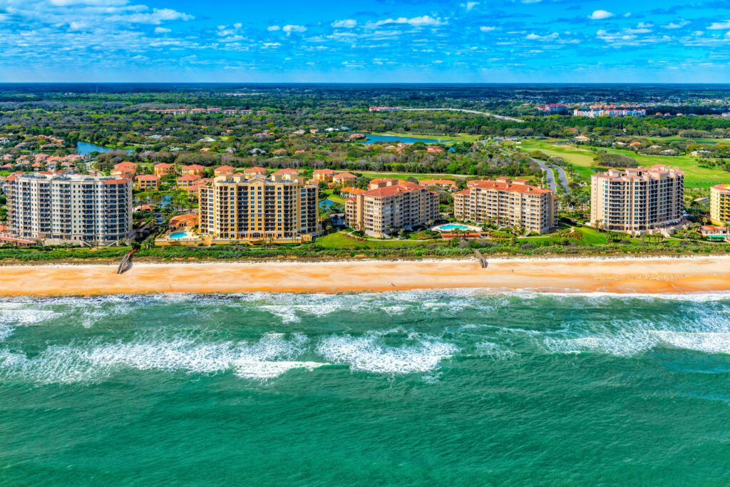 Aerial view of beachfront condominium buildings and vacation rentals located in Palm Coast, Florida near St. Augustine shot from an altitude of about 1000 feet over the Atlantic Ocean.
