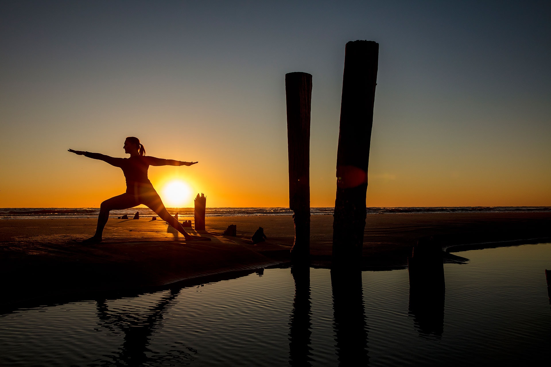 Silhouette of a woman doing yoga on the beach.