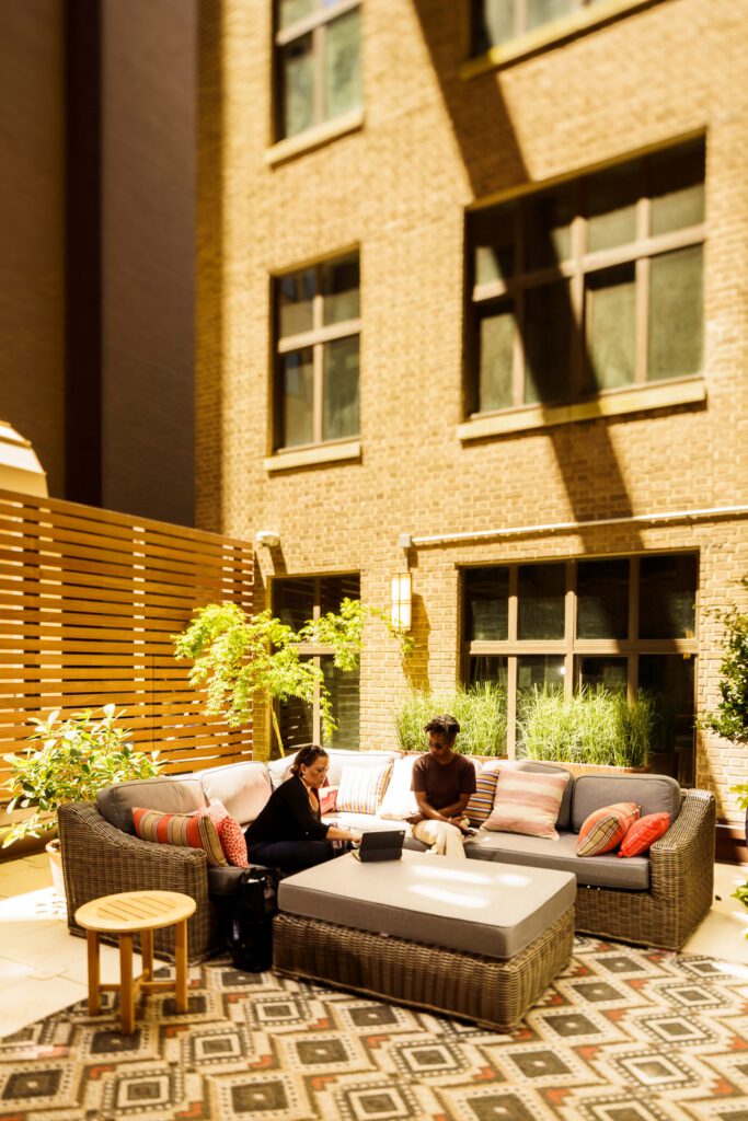 Two people lounge in an apartment courtyard filled with outdoor furniture.