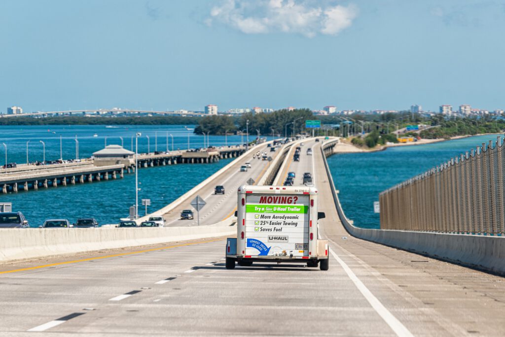 Bridge over Tampa Bay, Florida with Uhaul u-haul trailer attached to car vehicle for moving relocation to state on interstate highway road freeway