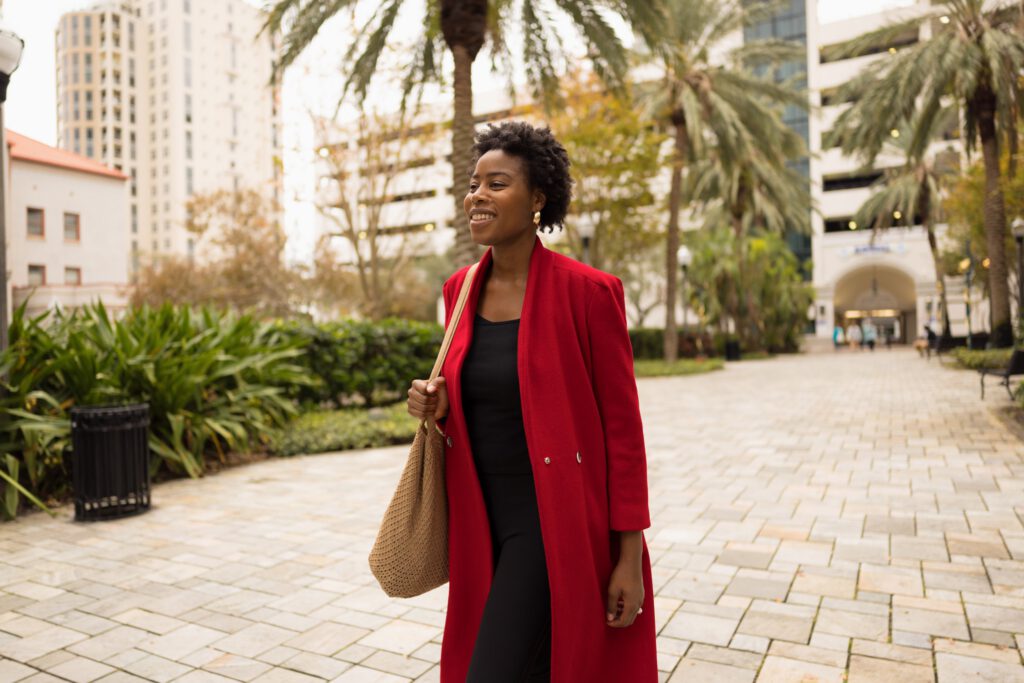 Young african-american businesswoman smiles while walking through a city park, enjoying her day.